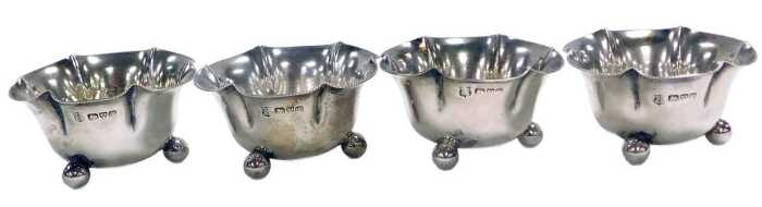 A set of four Edward VII silver salts, of flowerhead form, each raised on three ball feet,...