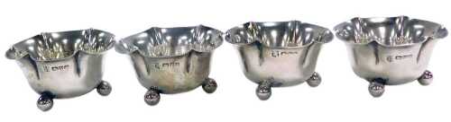 A set of four Edward VII silver salts, of flowerhead form, each raised on three ball feet,...