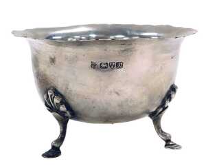 An Edward VII silver sugar bowl, with a frilled rim, raised on three foliate capped hoof feet,...