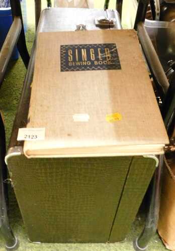 A cased Singer sewing machine, together with a Singer Sewing book.