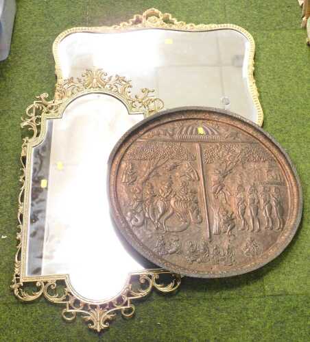 A copper repousse wall shield, featuring Hindu mythological scenes, together with a brass scroll...