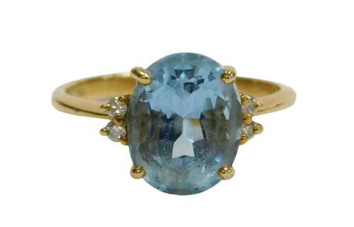 An aquamarine solitaire ring, in a claw setting with diamond set shoulders, in yellow metal...