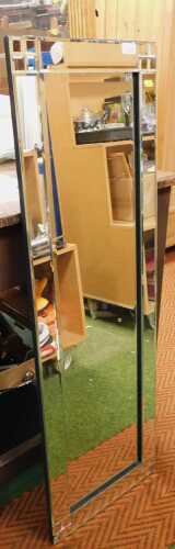 A three quarter length wall mirror, with bevelled glass and a geometric border design (AF).