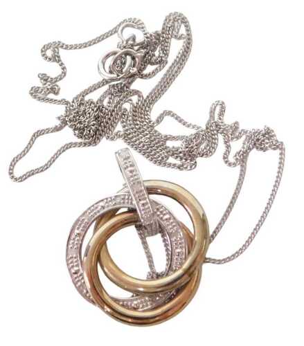 A three colour and diamond triple ring pendant, on a curb link neck chain, white metal, stamped...