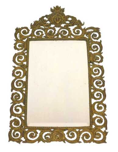 A late 19thC French brass wall mirror, with an embossed mask and foliate scroll decoration, with...