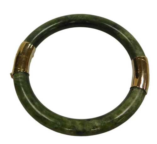 A Chinese jade bangle, with yellow metal mounts, on a snap clasp, with safety chain as fitted,...