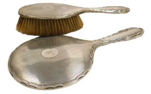 A George VI silver backed hand mirror and hairbrush, with engine turned decoration, circular...
