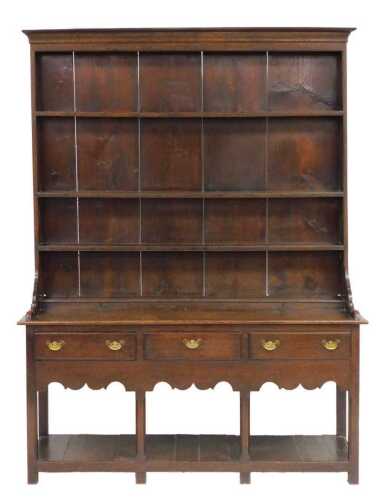 A George III oak dresser, the three shelf plate rack with an outswept pediment, above a base...