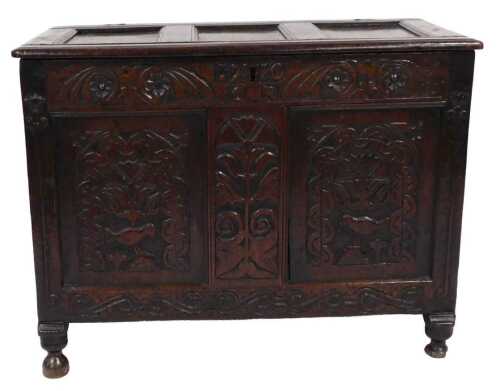 A Queen Anne oak coffer, with a triple panelled lid, above a carved frieze with flowers and...