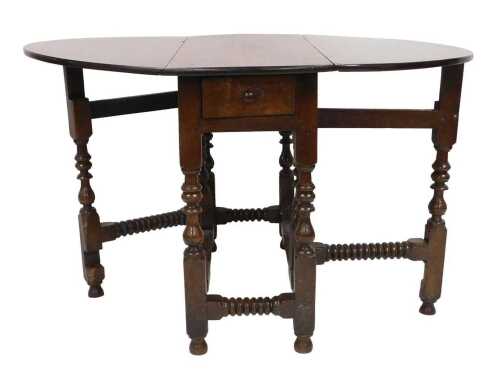 A Georgian oak drop leaf dining table, with a frieze drawer, raised on turned supports united by...