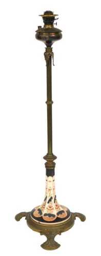 A Victorian brass and ceramic standard oil lamp, with a brass reservoir, the outswept ceramic...