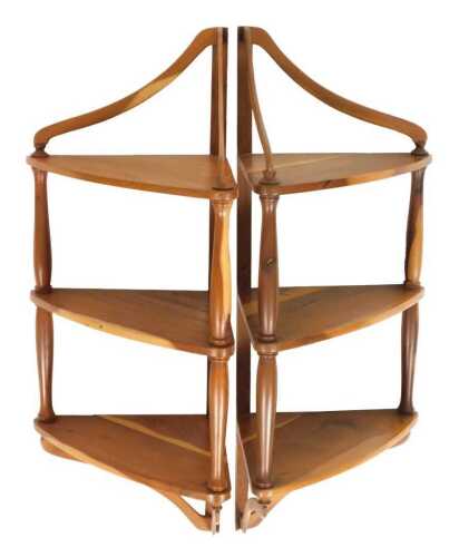 A pair of yew wood wall mounted corner display stands, of three shelf form, 60cm high, 30cm wide.