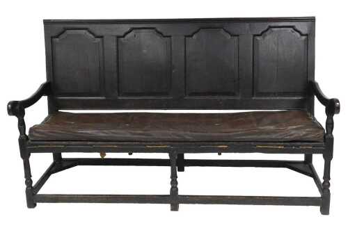 An 18thC oak settle, with a four panel back, scrolling arms, and later cushion seat, raised on...