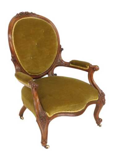 A Victorian mahogany nursing chair, with a floral carved crest rail, circular button back in...