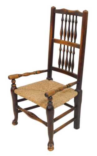 A 19thC rush seated spindle back chair, with turned arms, raised on cabriole legs united by a...