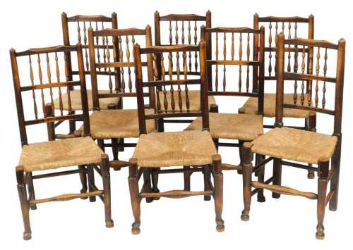 A set of eight Georgian oak spindle back rush seated country dining chairs, raised on turned...