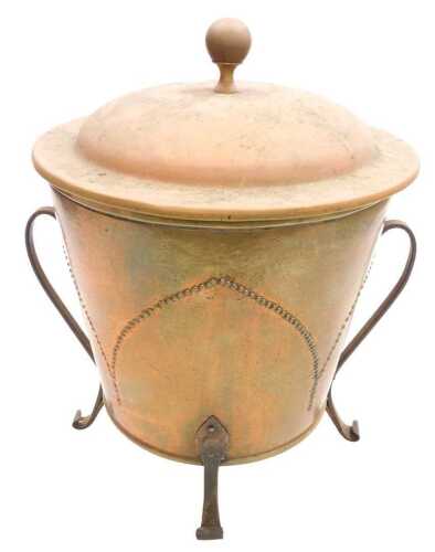 A Victorian Arts & Crafts brass coal bin, with lid, raised on four wrought iron feet, 44cm high.
