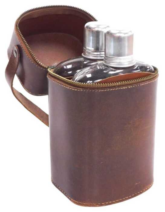 A pair of glass and tan leather bound hip flasks, named for Gin and Whisky, in a brown leather...