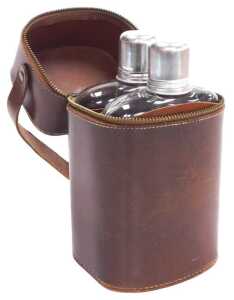 A pair of glass and tan leather bound hip flasks, named for Gin and Whisky, in a brown leather...