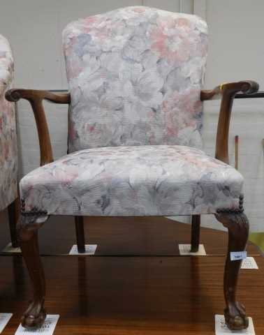 A walnut open armchair, upholstered in floral fabric, on cabriole legs with ball and claw feet.