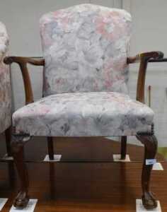 A walnut open armchair, upholstered in floral fabric, on cabriole legs with ball and claw feet.