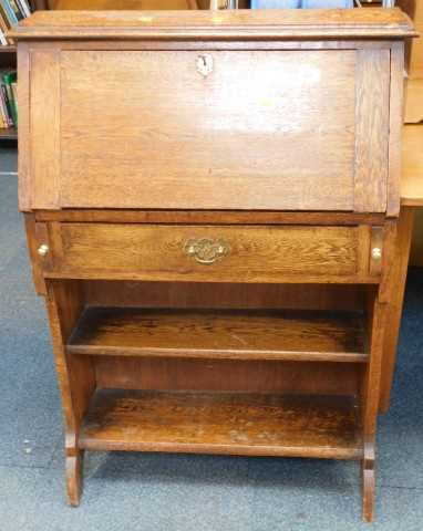 An oak student's desk, the fall enclosing a fitted interior, above a frieze drawer and two...