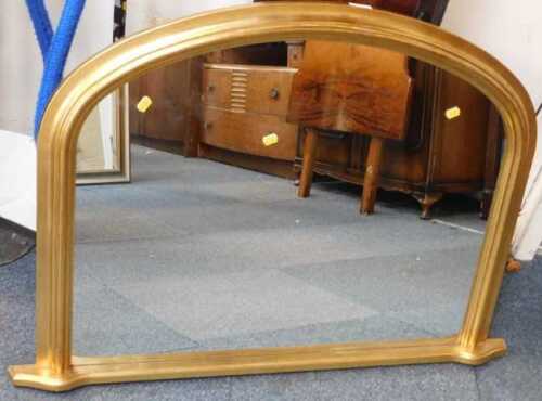 A Victorian style gilt overmantel mirror, with arched top, 73cm high, 103cm wide.