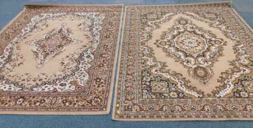 Two floral patterned Eastern style machine woven rugs, in brown and beige.