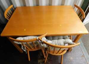 A beech kitchen table, of plain form, and four Ercol style kitchen chairs with spindle turned...