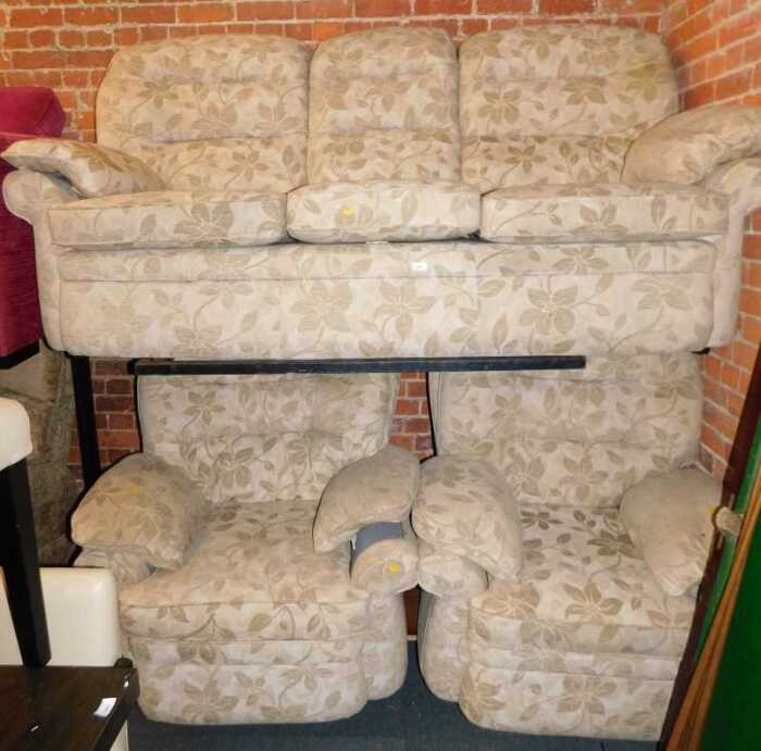 A lounge suite, comprising a three seater sofa, and two armchairs, upholstered in a light brown...