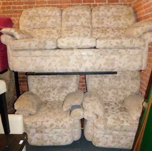 A lounge suite, comprising a three seater sofa, and two armchairs, upholstered in a light brown...