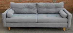 A contemporary grey upholstered three-seater sofa, raised on oak cylindrical tapering legs,... - 2
