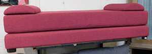 A modern red upholstered daybed, on ebonised feet, 74cm high, 188cm long, 225cm wide.