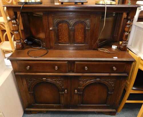 An oak court cupboard, with central door flanked by turned pillars, the base with two drawers...