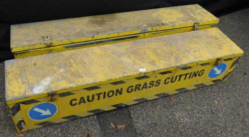 A pair of yellow painted galvanised metal storage boxes, each titled to the front "Caution Grass...