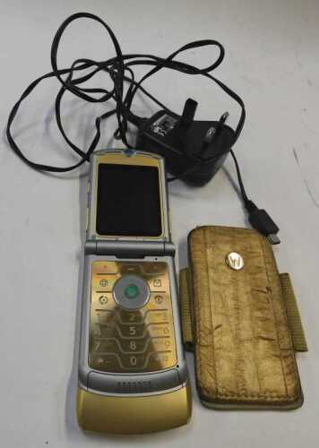 A Dolce and Gabbana Motorola limited edition flip phone, and charger, with additional case.