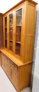 V - A light oak display cabinet, with three glazed doors raised above three central drawers, flanked...