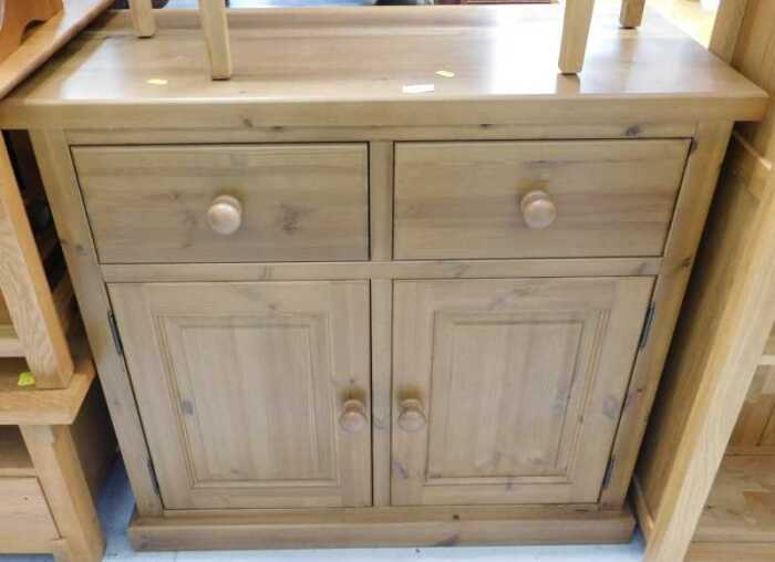 V - A pine side cabinet, with two drawers, raised above double cupboard. Note: VAT is payable on the...