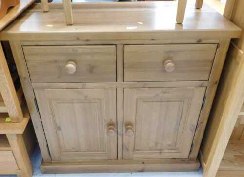V - A pine side cabinet, with two drawers, raised above double cupboard. Note: VAT is payable on the...