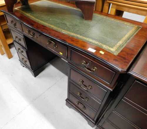 A mahogany finish twin pedestal desk, with three frieze drawers raised above six further drawers...