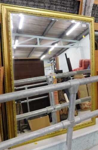 A hanging mirror and gilt coloured frame, with bevelled glass.