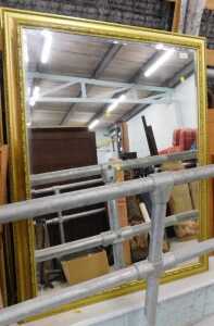 A hanging mirror and gilt coloured frame, with bevelled glass.