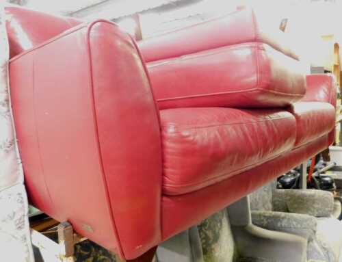 A two-piece Violino lounge suite, comprising three seater sofa and footstool, in red leather.