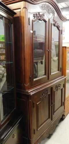 A heavily carved display cabinet, with arched top and floral frieze above two doors with raised...