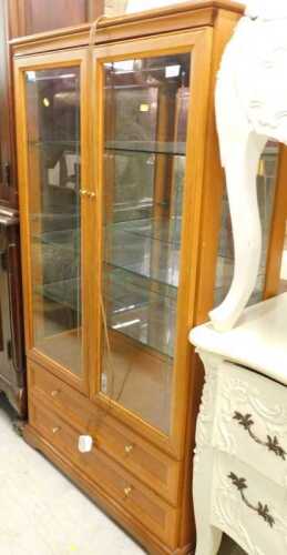A teak display cabinet, with two doors revealing adjustable glazed shelves, above two long...