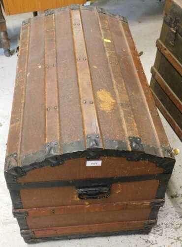 An early 20thC dome topped trunk, with metal and wooden banding, and side carrying handles.