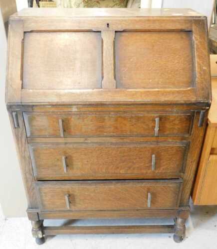 An oak bureau of small proportion, the fall revealing a fitted interior above three long drawers,...