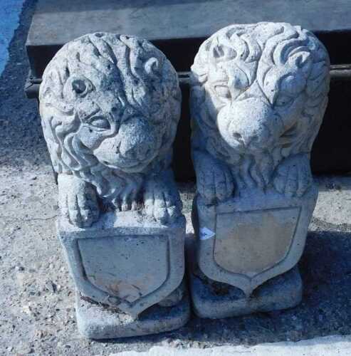 A pair of garden statues or plinth tops, lions with shields.