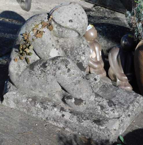 A garden statue of a seated figure, on rectangular base.