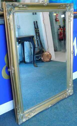 A modern bevel edged mirror, in elaborate gilt coloured frame.